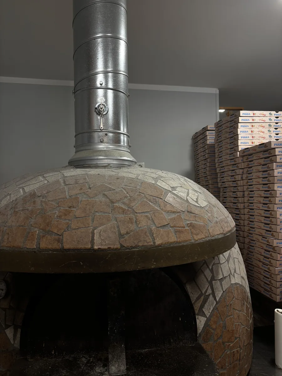La cúpula de mosaico de nuestro horno de leña, en teselas ocre y gris, con la boca apagada debajo.